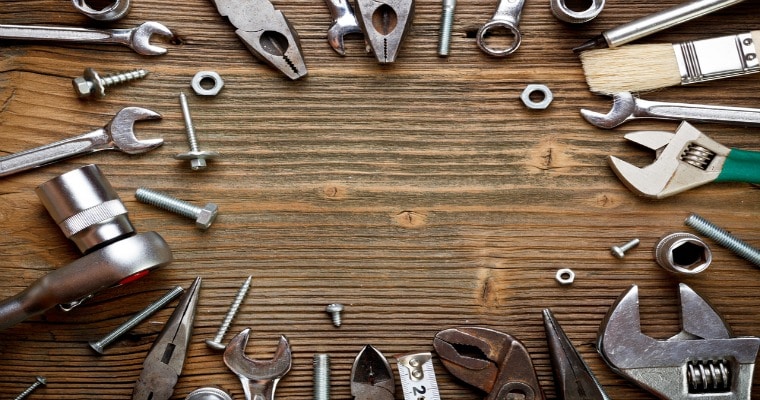 Tools - including nails, wrenches, and pliers - arranged in a circle on a wooden table.