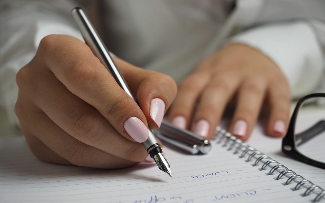 A woman's hands writing in a notebook showing the value of seeking strategic advice from both internal and external sources.